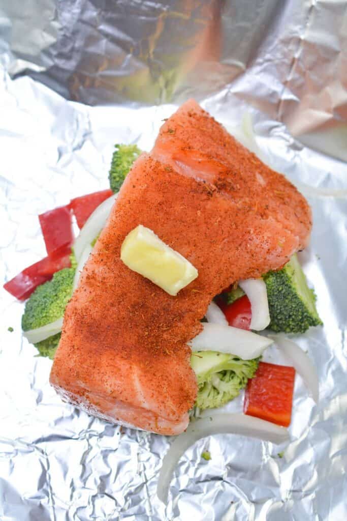 Butter on top of salmon fillet resting on vegetables.