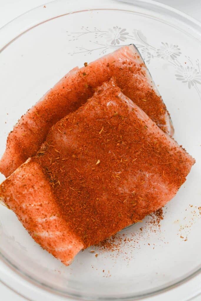 Salmon fillets with seasoning on top.