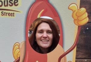 Imge of Simone from Keto Recipe Ideas with her head through a giant sausage cut out.
