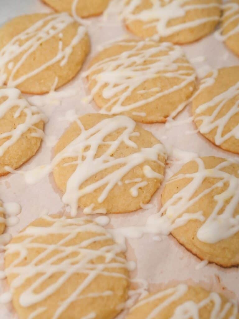 Keto Italian lemon cookies drizzled with sugar-free lemon glaze on parchment paper.