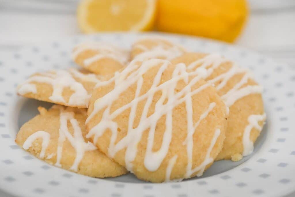 Keto Italian lemon cookies with sugar-free glaze served on a plate with fresh lemons.