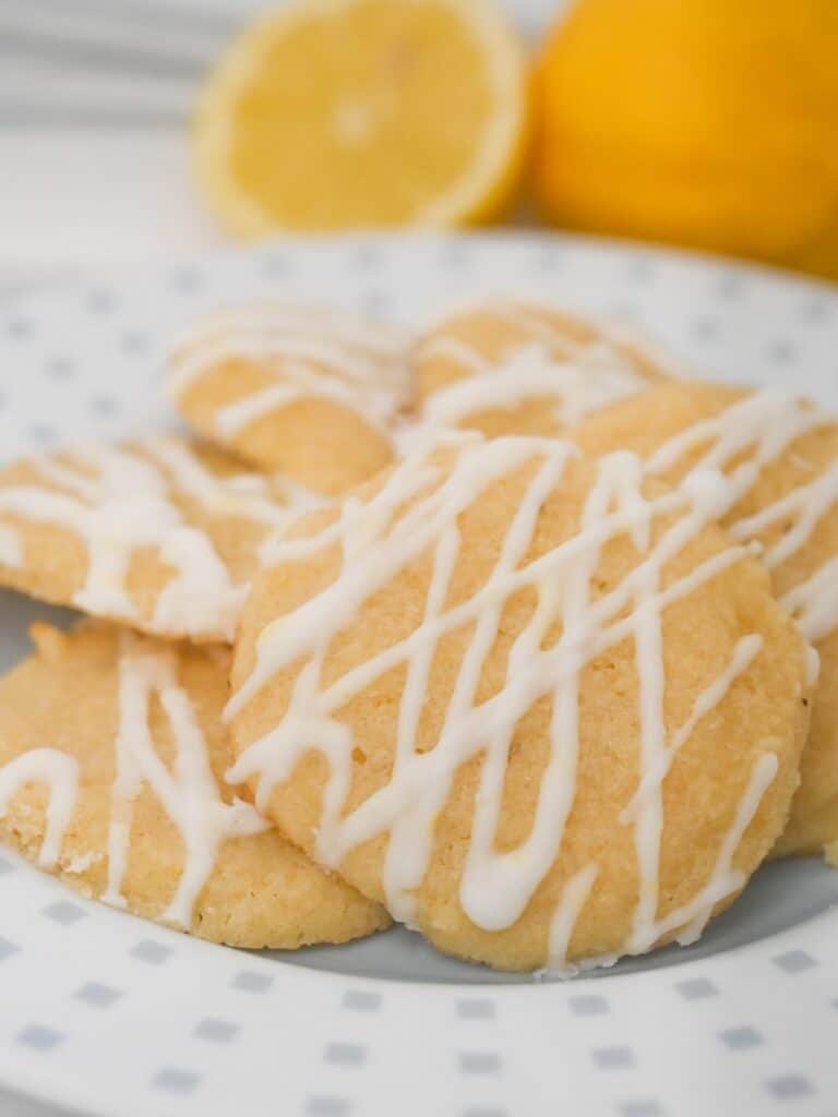 Keto Italian lemon cookies with sugar-free lemon glaze served on a plate with fresh lemons.